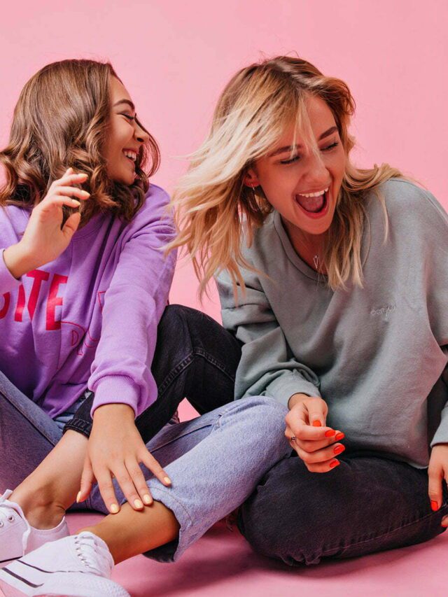 Laughing girls in white gumshoes fooling around with their pet. Studio portrait of caucasian curly